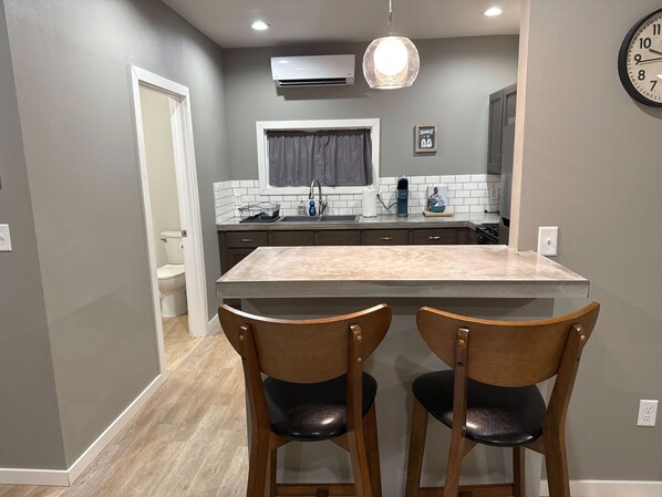 A modern kitchen with a central island, two wooden chairs, and a hanging light fixture. - Grand Getaways Apt. #2 (Duluth)