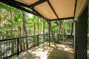 A covered wooden deck with a metal railing, surrounded by dense tropical vegetation. - Tiona Palms Holiday Park (Tiona)
