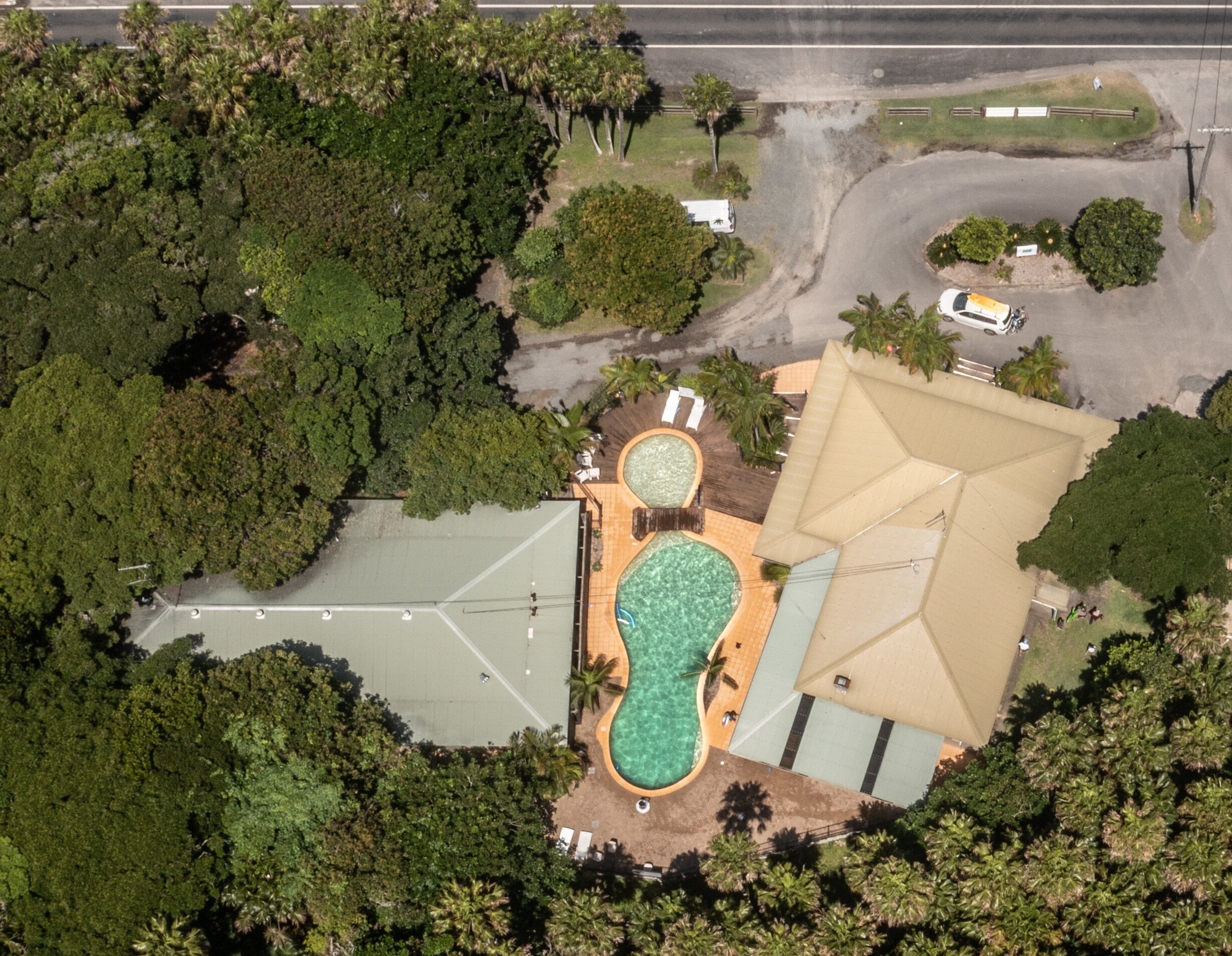 An aerial view of a resort with a swimming pool, tennis courts, and lush greenery.