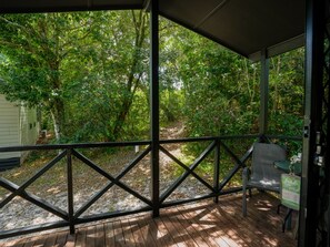 A covered wooden deck with a metal railing, overlooking a forested area. - Tiona Palms Holiday Park (Tiona)