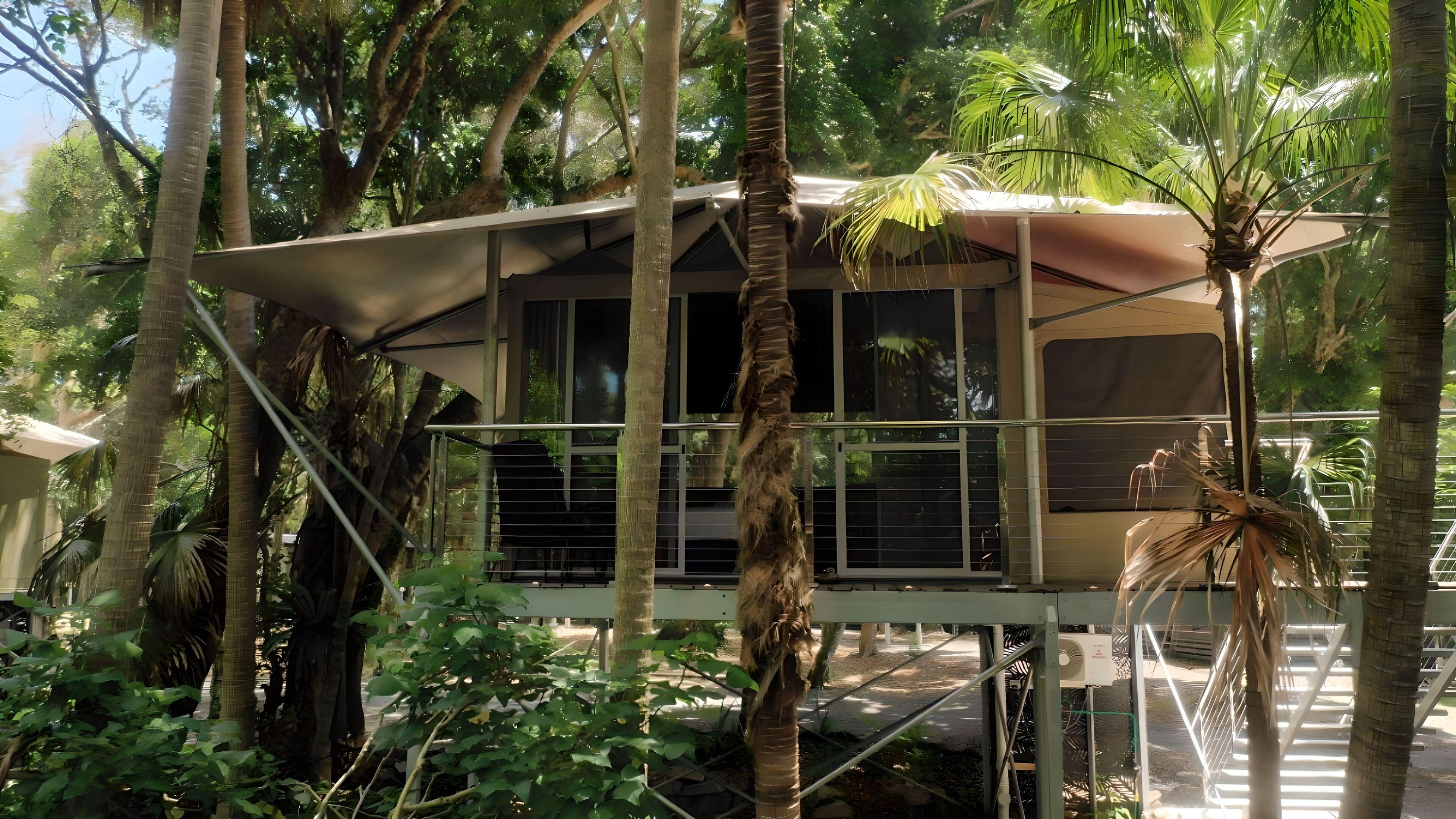 A small, elevated wooden structure with a sloped roof, surrounded by dense tropical foliage.