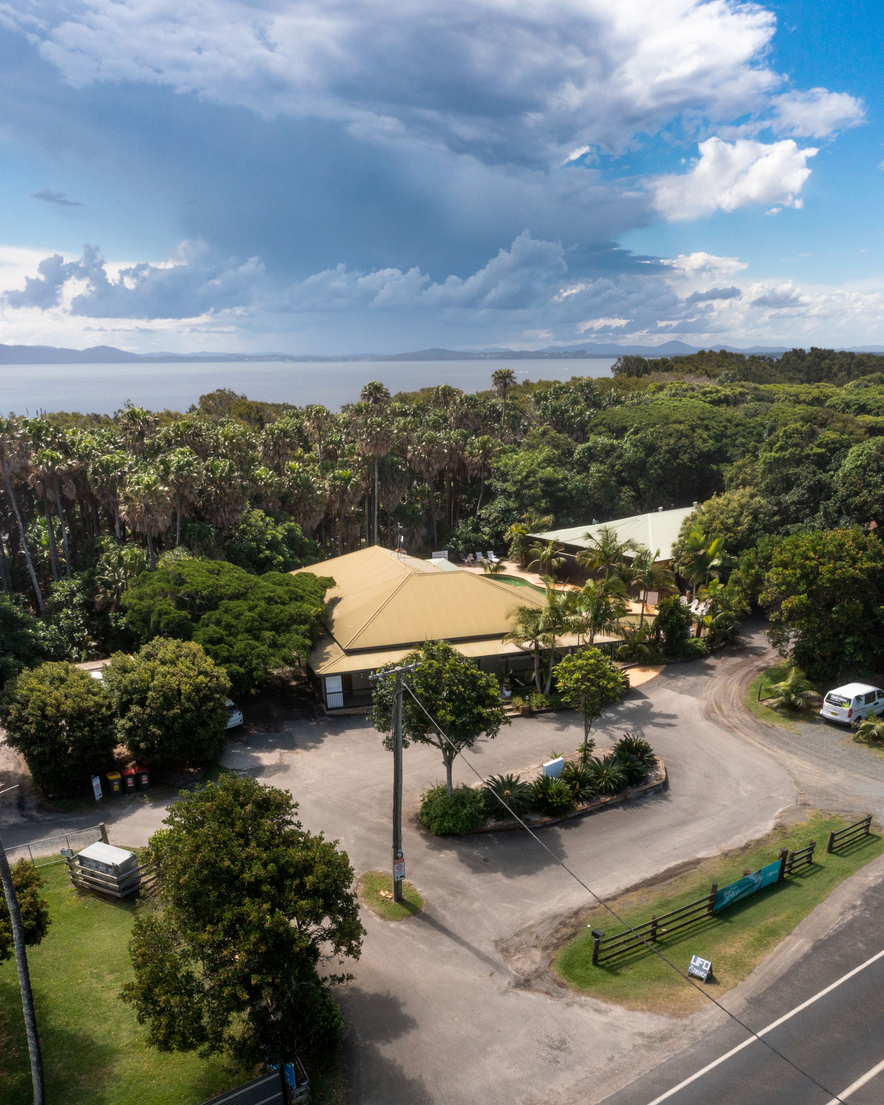 An aerial view of a property with a large building, surrounded by dense greenery and a road.
