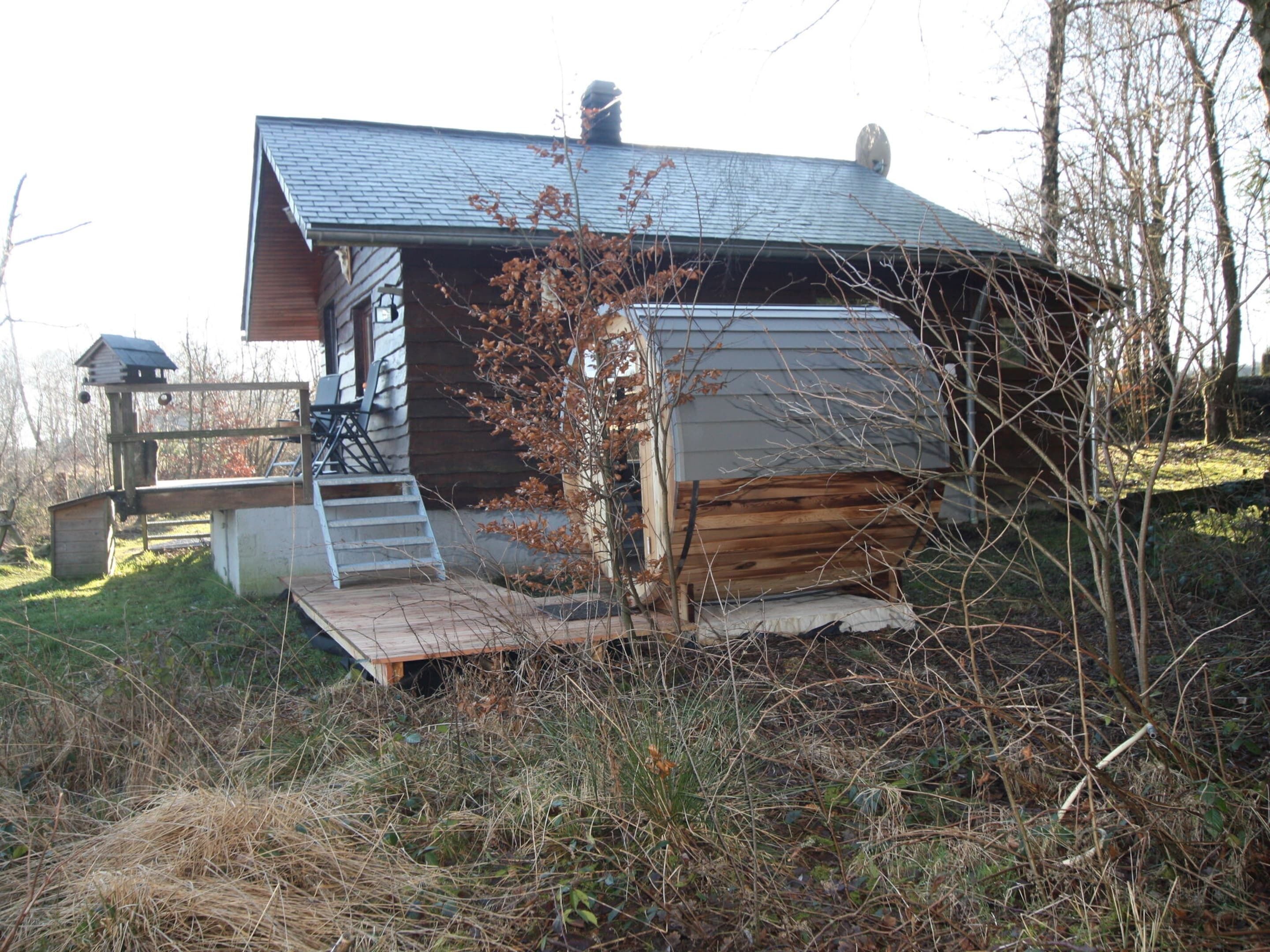 Une cabane rustique avec un toit en pente, une terrasse en bois et un petit espace porche.