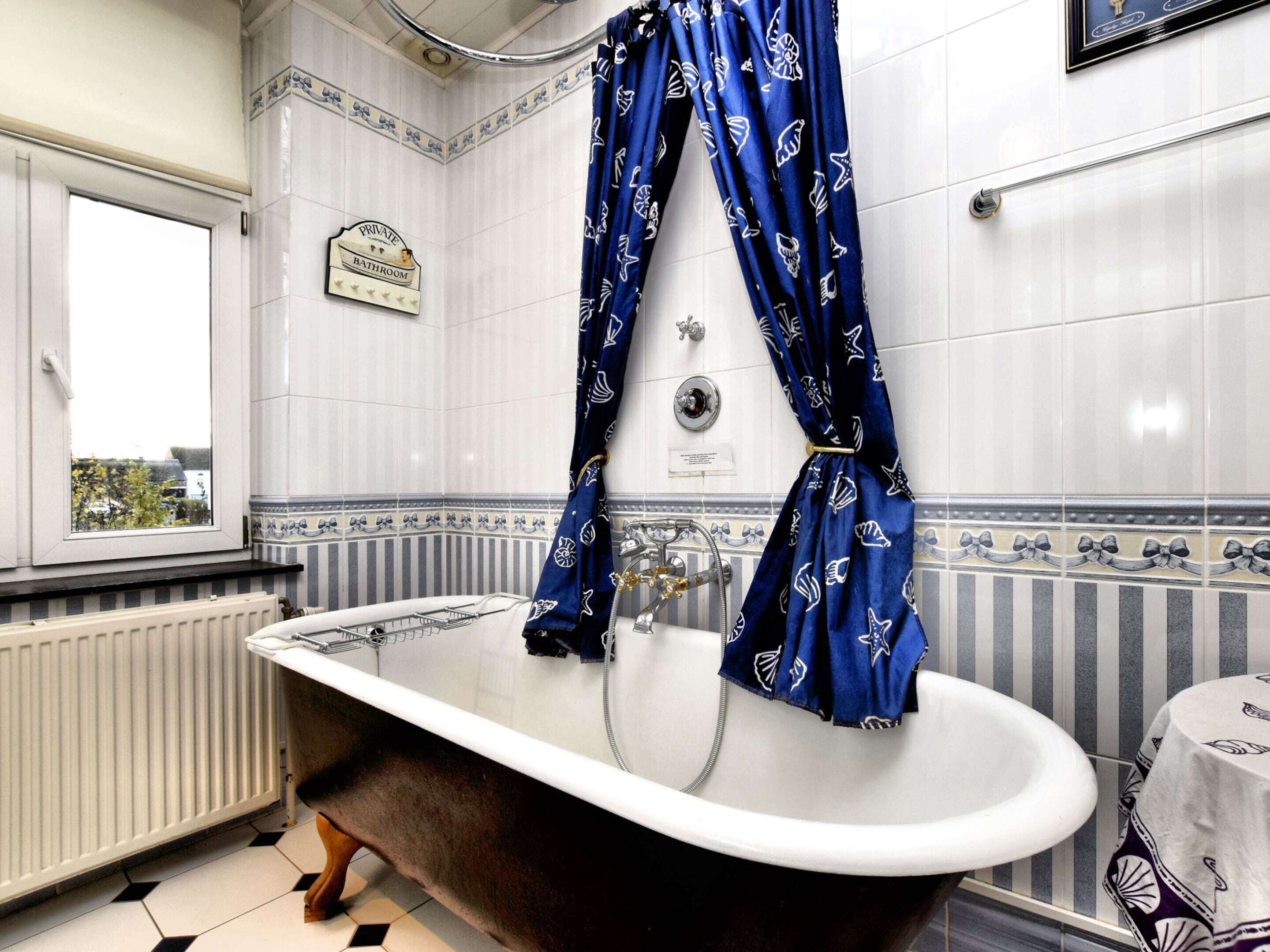 Un baño con bañera tipo patas de león, una ventana y un letrero que indica que es un baño privado.