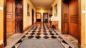 Un pasillo de hotel con puertas de madera, pisos de baldosas a cuadros y un banco.