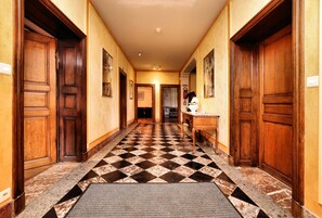 A hotel hallway with wooden doors, checkered floor tiles, and a bench. - Stylish Stay With Sauna (Houyet)