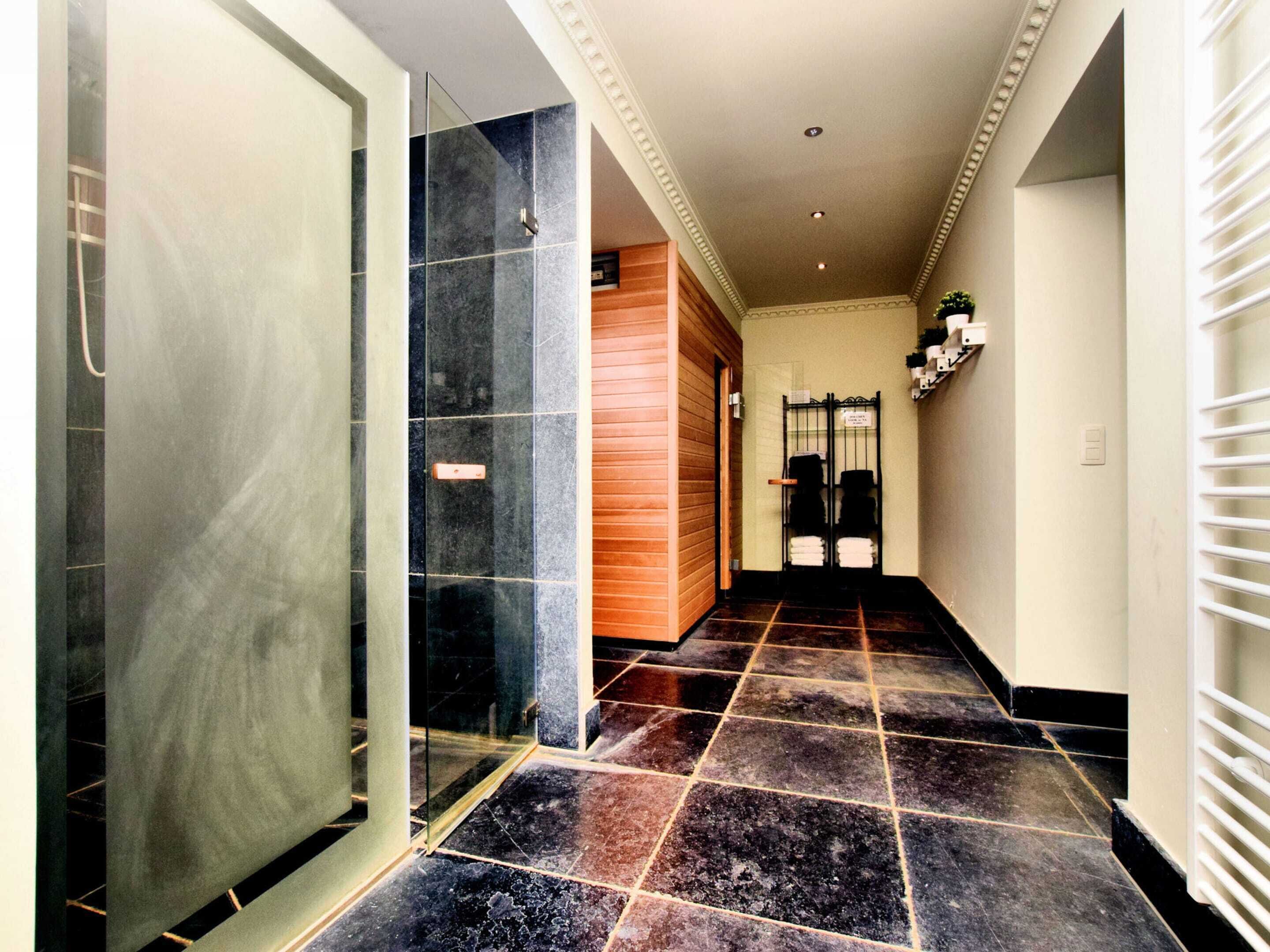 Un couloir avec une porte en verre, une porte en bois et un sol carrelé.