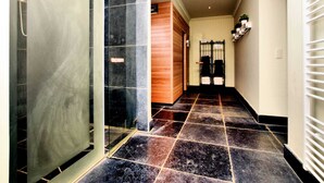 Un pasillo con puerta de cristal, puerta de madera y suelo de baldosas.