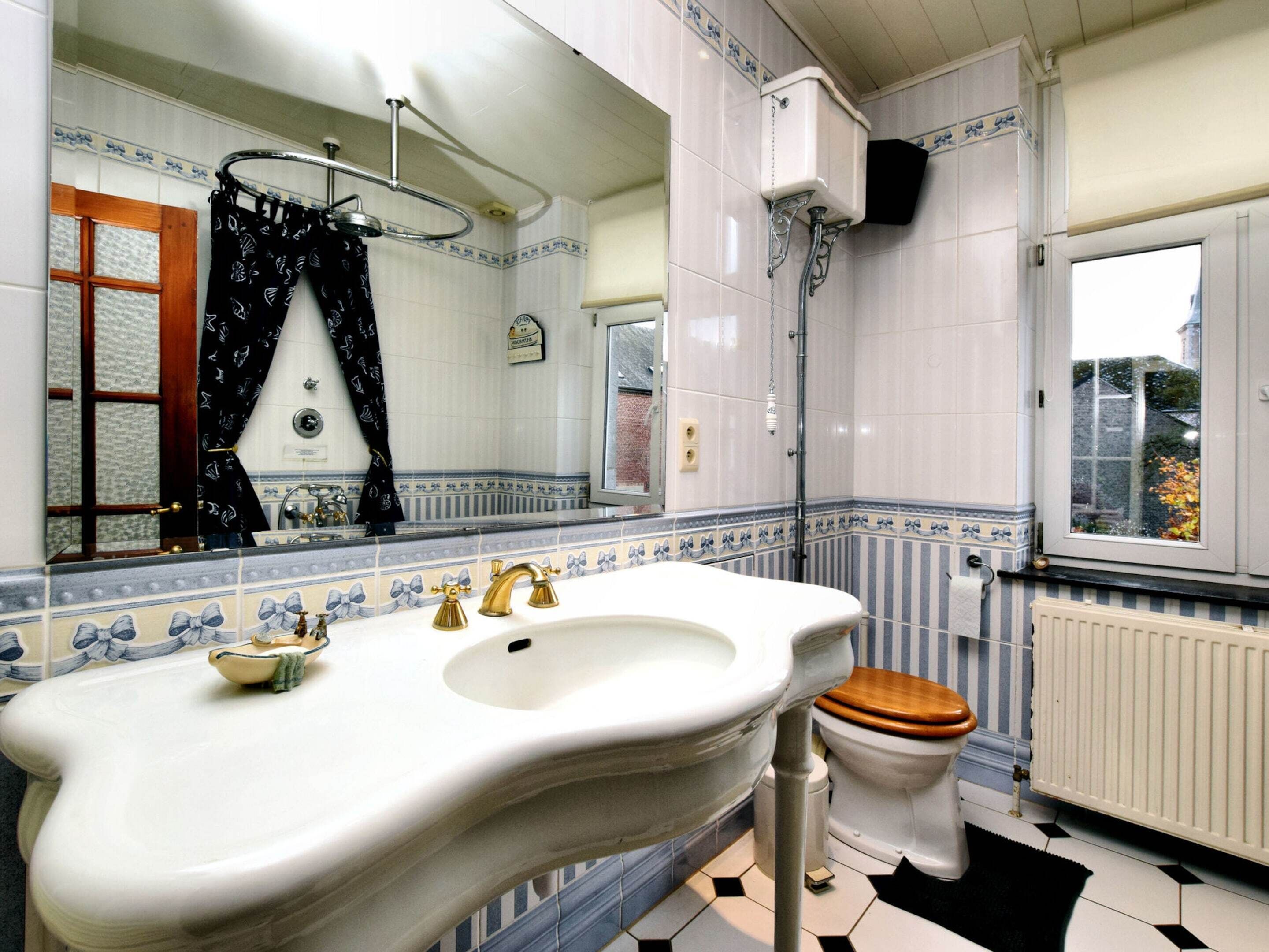 A bathroom with a white sink, a wooden toilet, and a mirror above the sink.