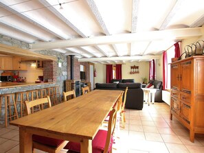Amplia sala de estar con una mesa de comedor de madera, varias sillas, un sofá y una cocina con pared de piedra y armarios de madera.