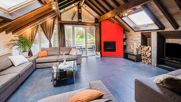A spacious loft with a high ceiling, a fireplace, a sofa, and a TV.