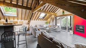 An attic-style room with a high ceiling, exposed wooden beams, a large window, and a red accent wall. - Charming Cottage with Hot Tub & Sauna, High Fens (Waimes)