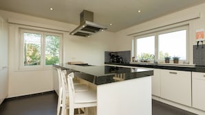 Une cuisine moderne dotée d’un grand îlot central, de meubles blancs et d’une fenêtre laissant entrer la lumière naturelle.