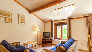 Ein gemütliches Wohnzimmer mit zwei karierten Sofas, einem kleinen Tisch, einer Lampe und einem Fernseher auf einem Holzgestell.