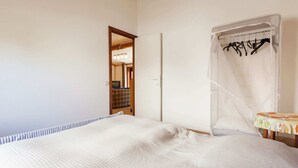 Ein Schlafzimmer mit Bett, Nachttisch, Kleiderschrank und einem durchgegangenen Tür sichtbaren Badezimmer.