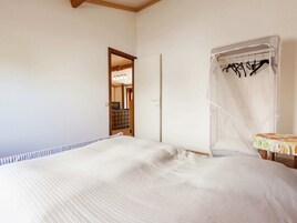Un dormitorio con cama, mesita de noche, armario y baño visible a través de una puerta abierta.
