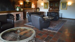 A living room with a fireplace, leather sofas, a coffee table, and a patterned rug. - Romantic Mansion in Strotzbusch by the Forest (Strotzbusch)