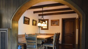 A dining area with a wooden table and chairs, a bench, and a hanging light fixture. - Romantic Mansion in Strotzbusch by the Forest (Strotzbusch)