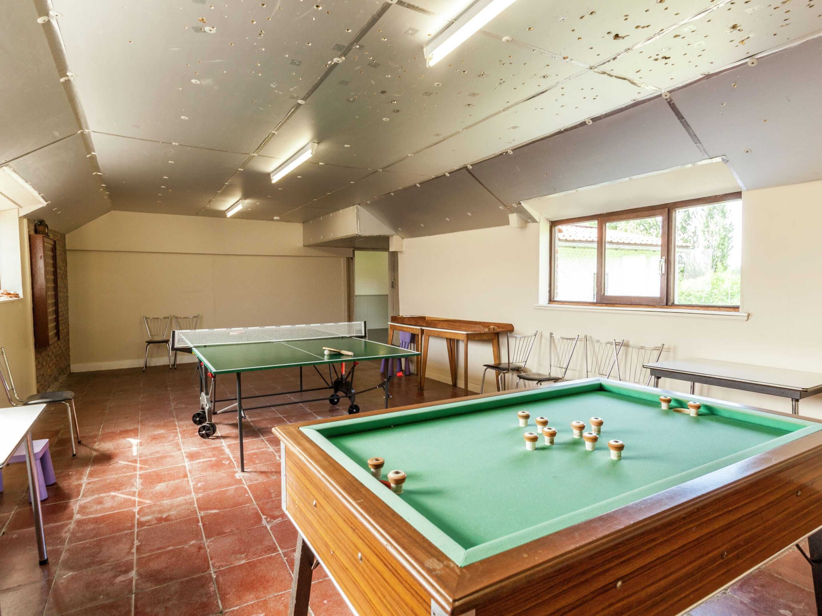 A room with a pool table, two ping pong tables, and a billiards table.