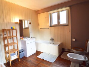 Un bany amb terra de fusta, un lavabo blanc, una banyera i un vàter.