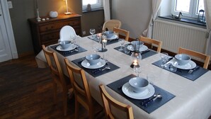 A dining room with a table set for four, including plates, glasses, and cutlery. - Stone-built Holiday Home in Dinant With Terrace (Dinant)