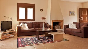 Ein Wohnzimmer mit zwei Sofas, einem Couchtisch, einem Fernseher und einem Kamin.