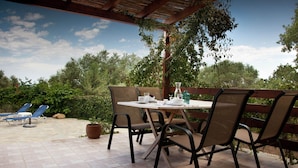 Eine Terrasse im Freien mit Esstisch und Stühlen, umgeben von einem überdachten Bereich mit Holzboden.