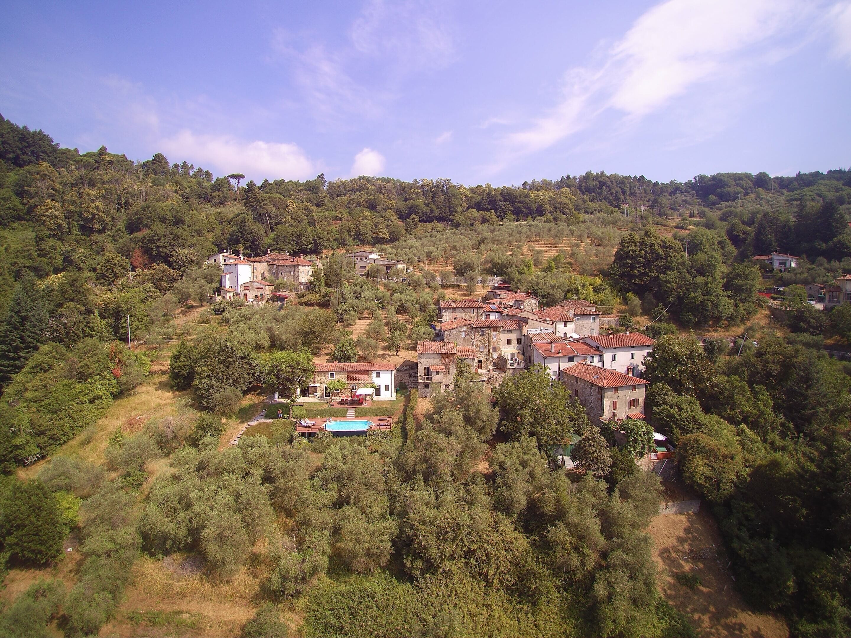 Un village perché sur une colline, avec des bâtiments traditionnels en pierre et une piscine.