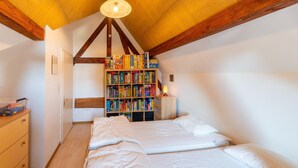 A bedroom with a wooden ceiling, a bookshelf, a bed, and a nightstand. - Ludogite: Lover's Retreat (Waimes)
