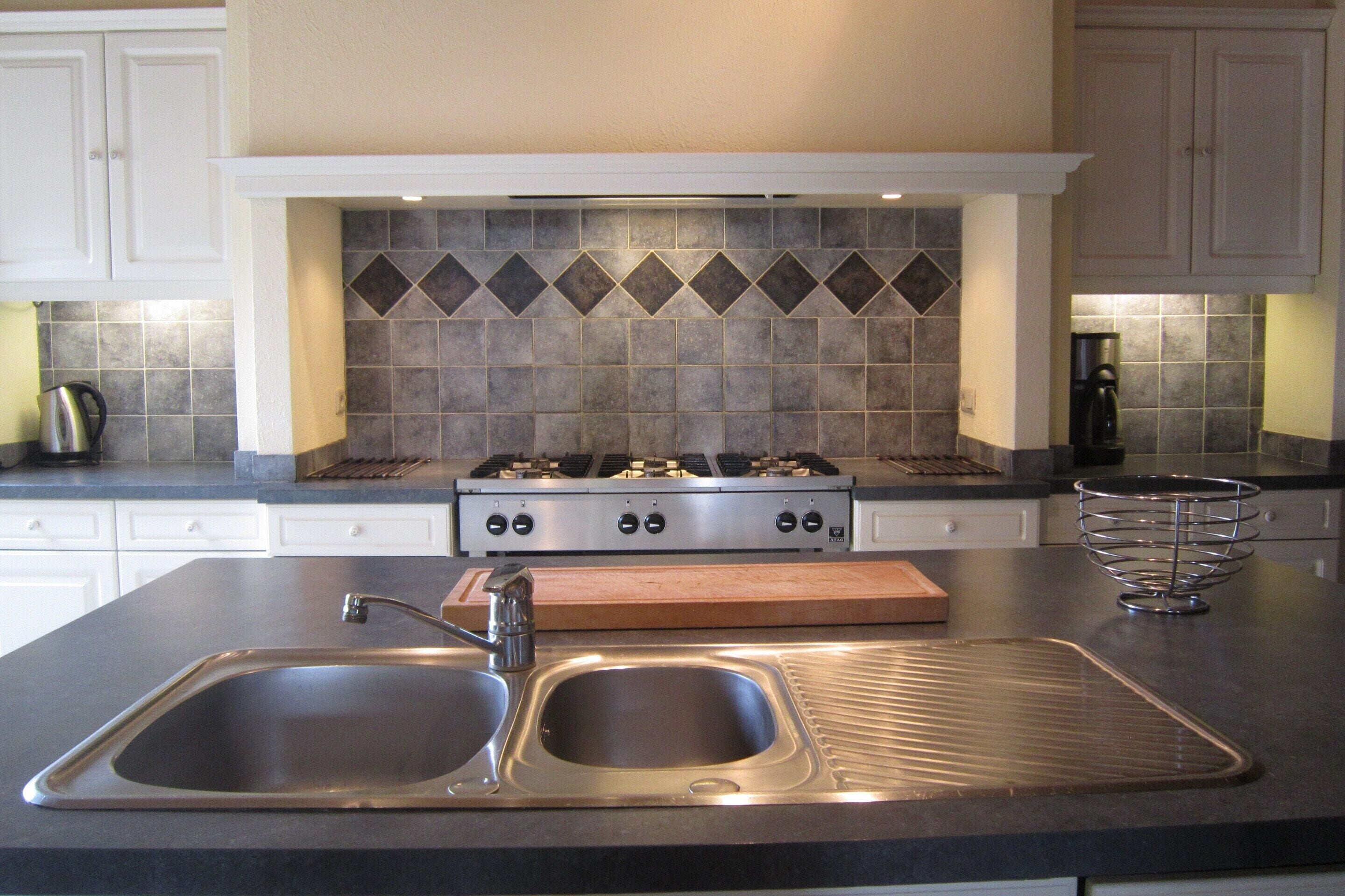 A kitchen with a double sink, a stove, and a coffee maker.