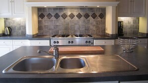Una cocina con un lavaplatos doble, una estufa y una cafetera.