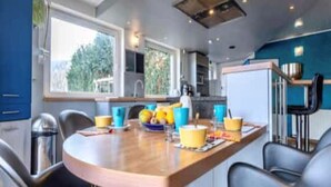 Cozinha moderna com mesa de madeira, cadeiras e vista para o exterior.