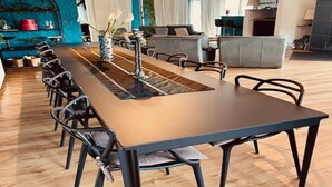 Uma sala de jantar moderna com uma mesa comprida, cadeiras e uma ilha central com um vaso de flores.