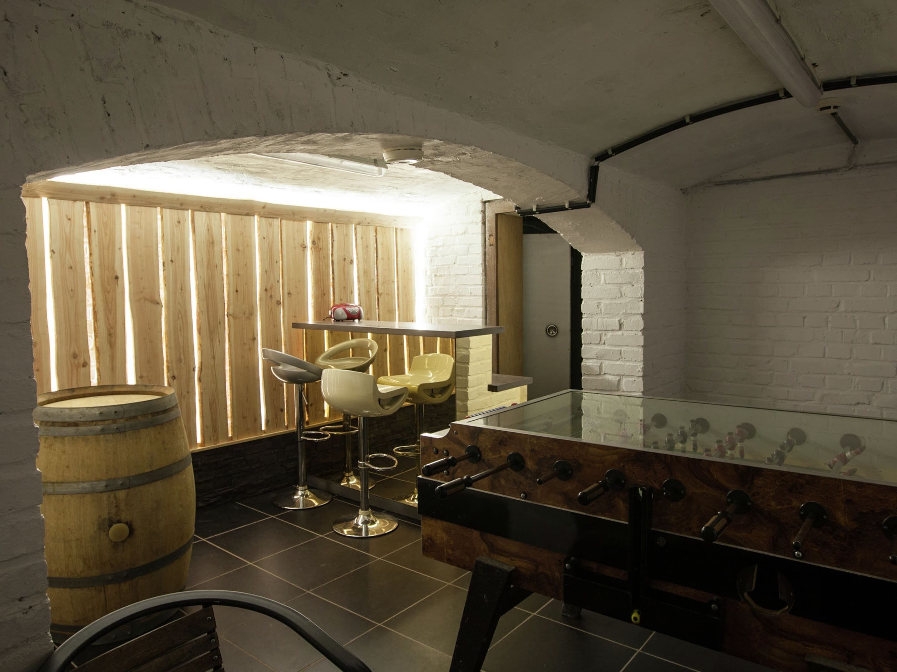 Un coin bar rustique avec des lambris en bois, un baby-foot et un tonneau à vin.