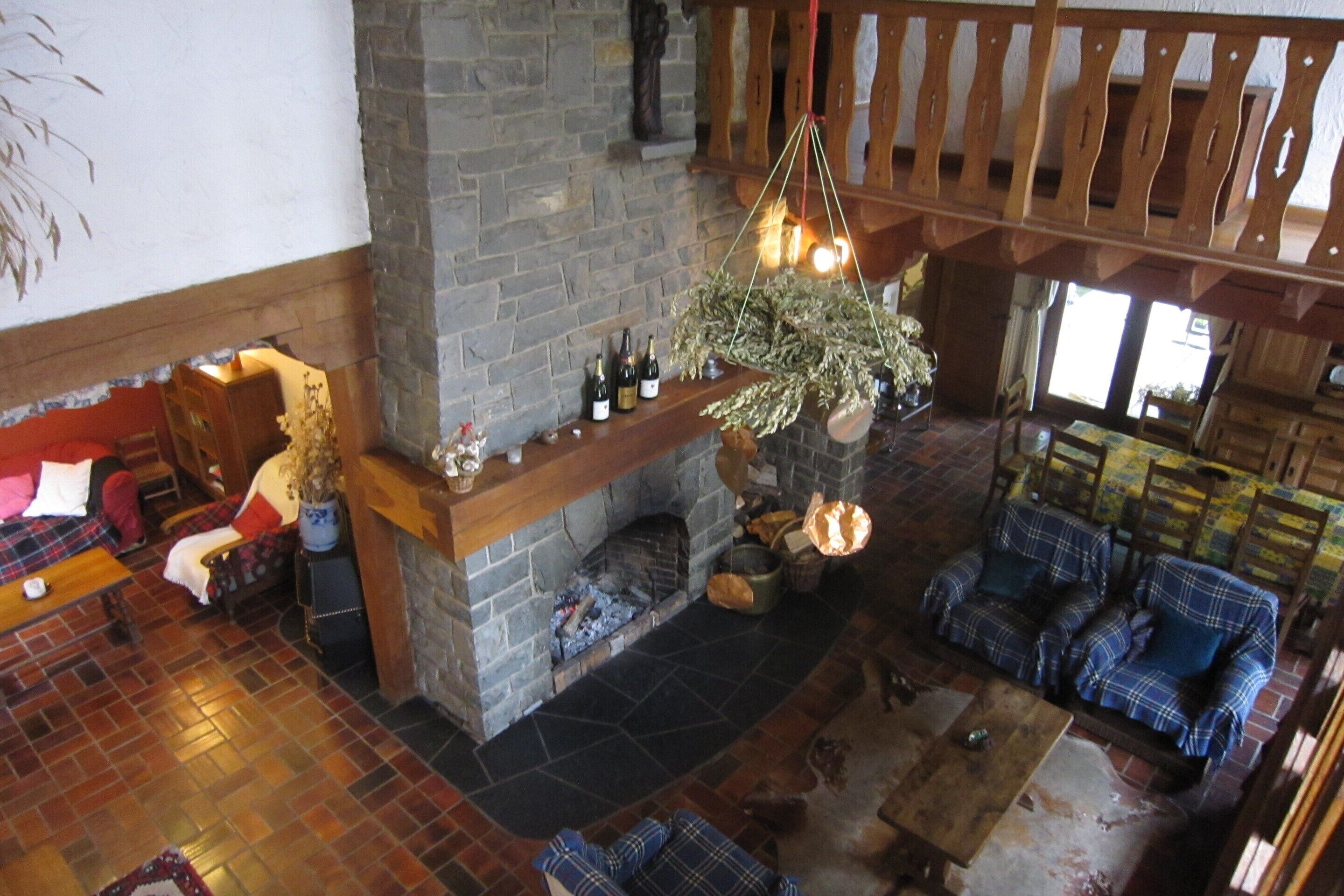 A spacious living area with a stone fireplace, plaid furniture, and a hanging light fixture.