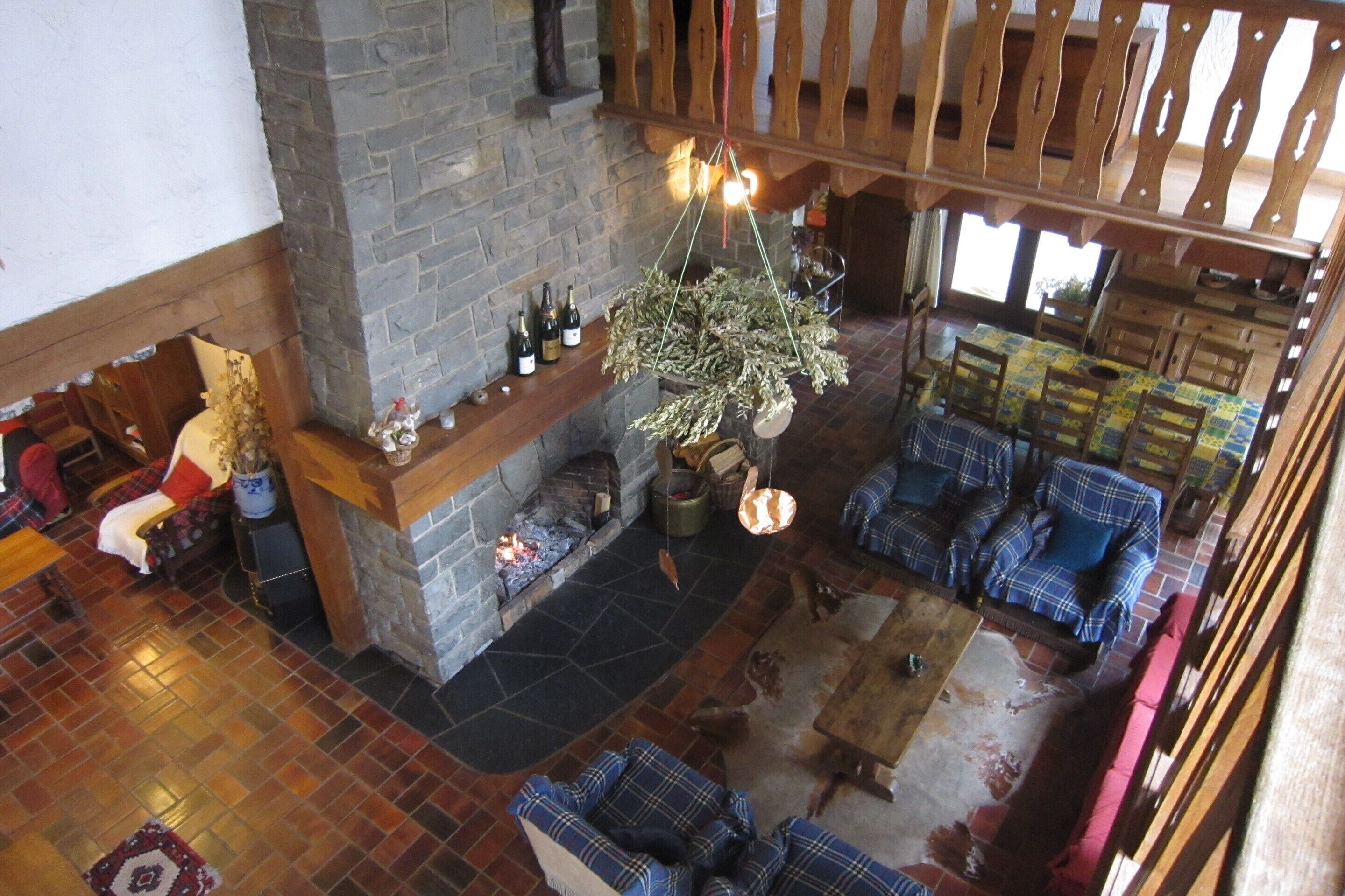 A spacious living area with a stone fireplace, wooden furniture, and a view of the outdoors.