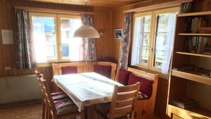 Une cabane en bois avec une table à manger, des chaises, un banc et une bibliothèque.