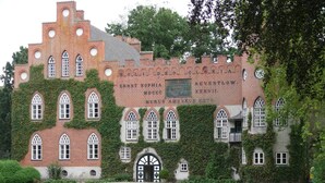 A historic building with ivy-covered walls and arched windows, featuring a plaque with inscriptions. - Beautiful Authentic Mill Close to the Beach (Wangels)