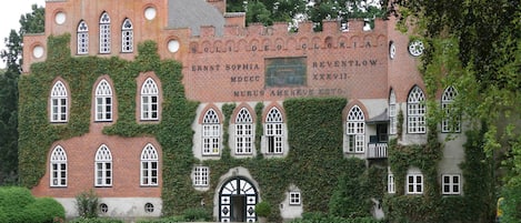 A historic building with ivy-covered walls and arched windows, featuring a plaque with inscriptions.