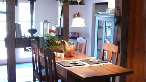 A wooden dining table with chairs, a vase with flowers, and a bird sculpture. - Beautiful Authentic Mill Close to the Beach (Wangels)