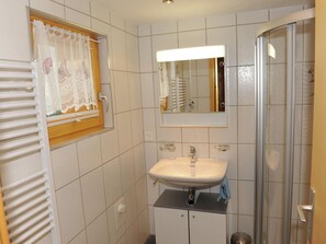 A compact bathroom with a sink, mirror, and shower.