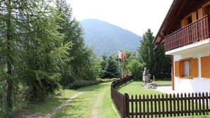 Une maison avec un balcon en bois, un chemin de pierre et un drapeau.