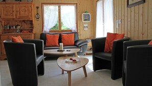 Un salon confortable avec un canapé, deux fauteuils, une table basse et une bibliothèque.
