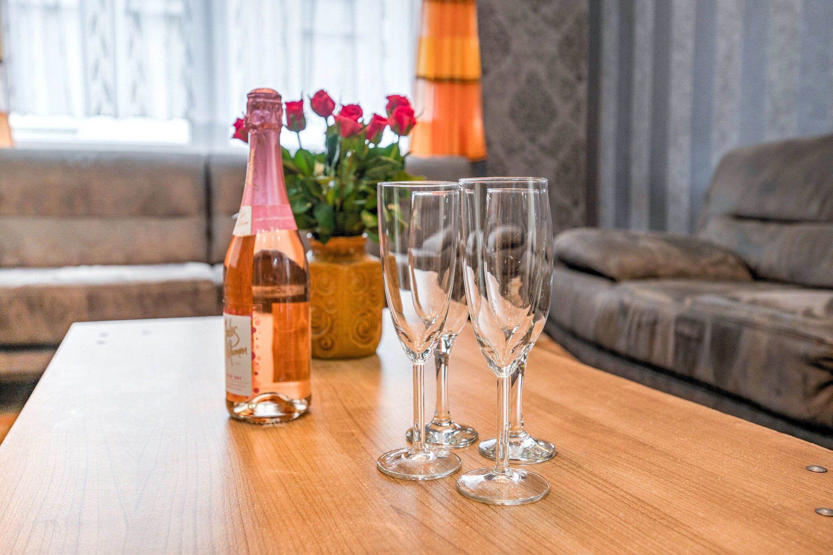 A wooden table with a bottle and three glasses on it.