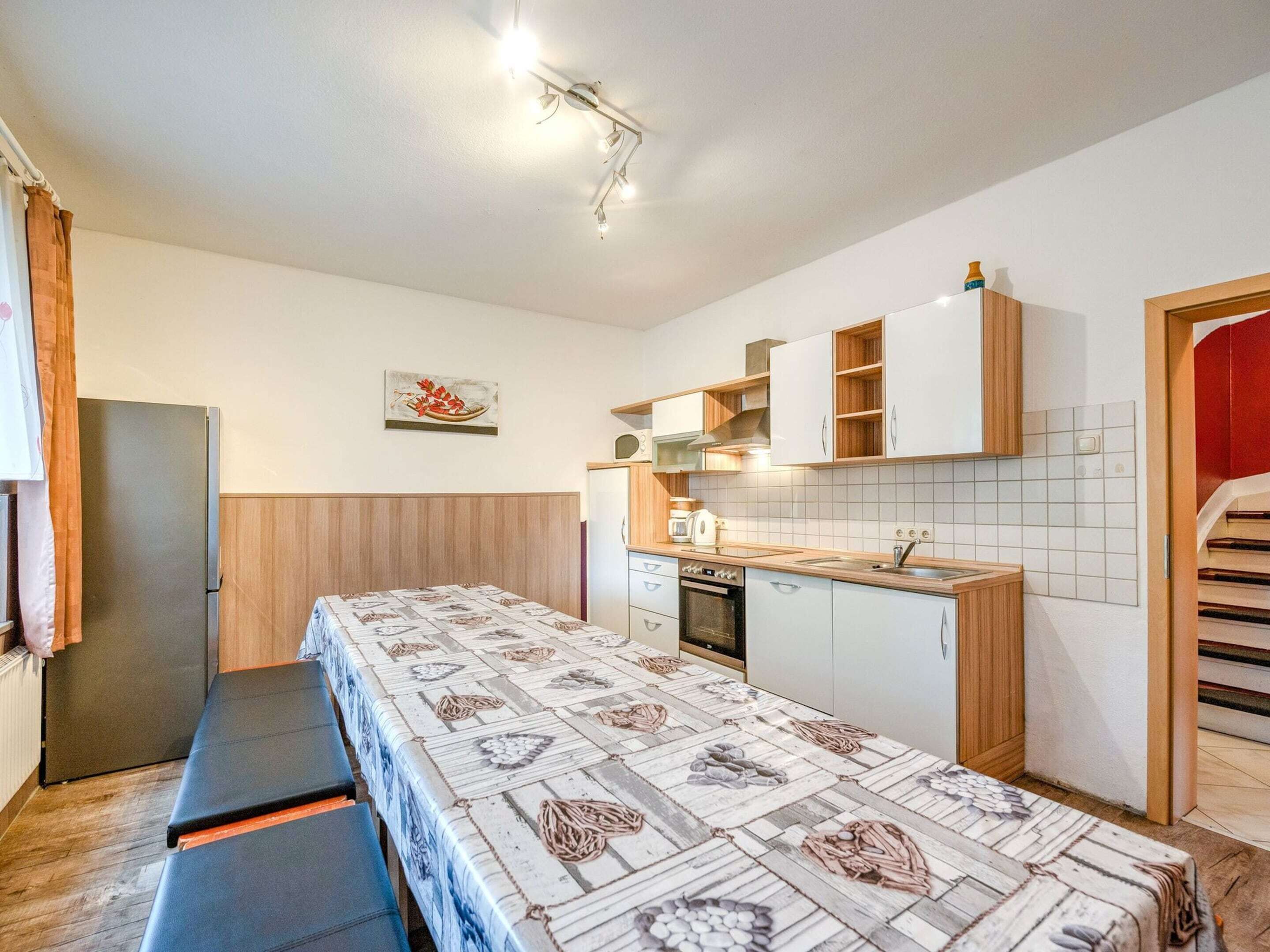 Une cuisine compacte comprenant une table à manger, un banc et un petit four.