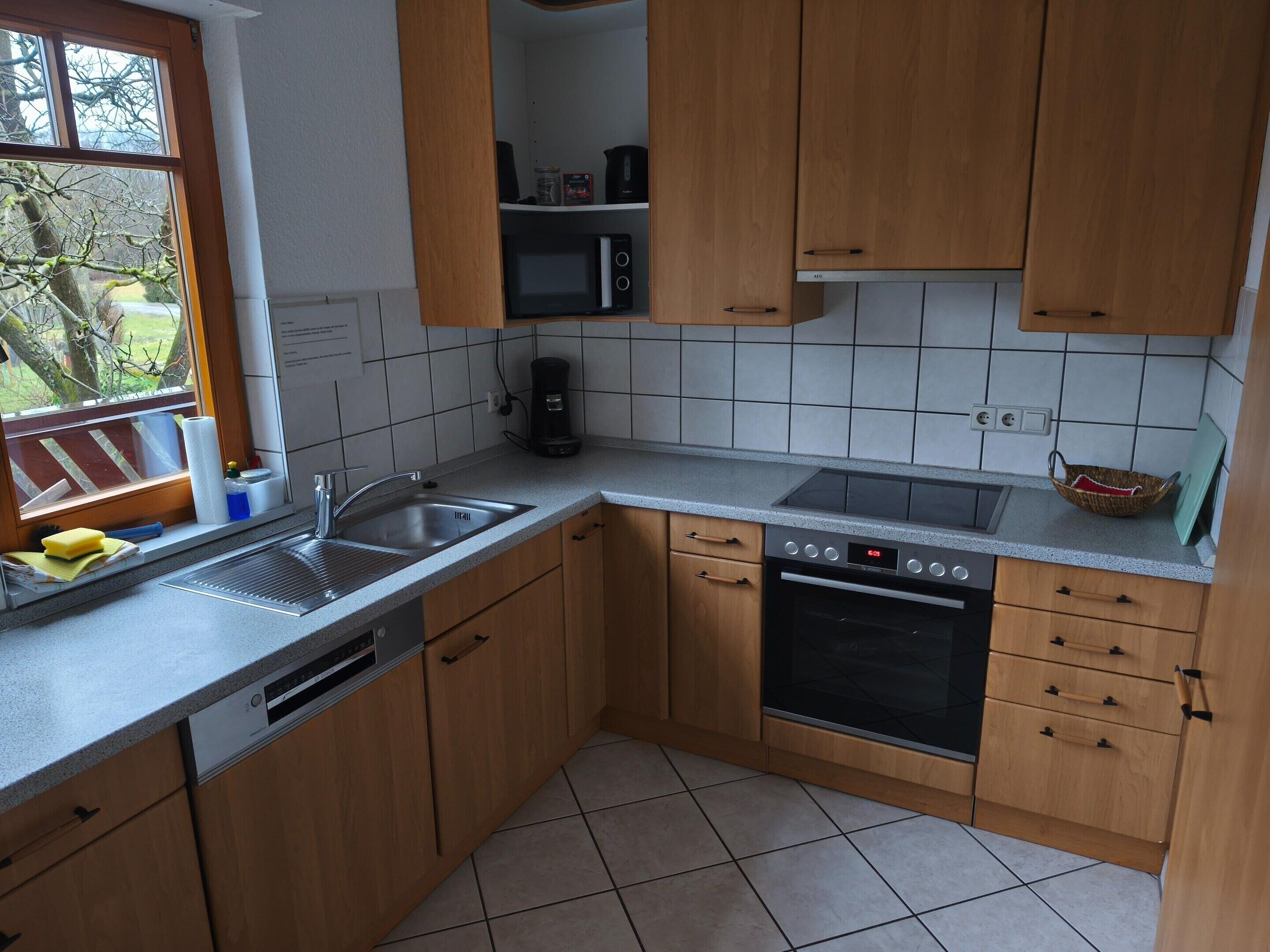 Une cuisine avec des meubles de rangement en bois, un lave-vaisselle, un four à micro-ondes et une cuisinière.