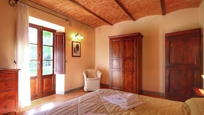 Een slaapkamer met een bed, een stoel, een kledingkast en een dressoir.