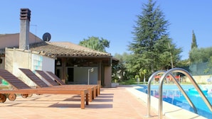 Un espace aménagé au bord de la piscine, avec des chaises longues, une piscine et un coin salon abrité.
