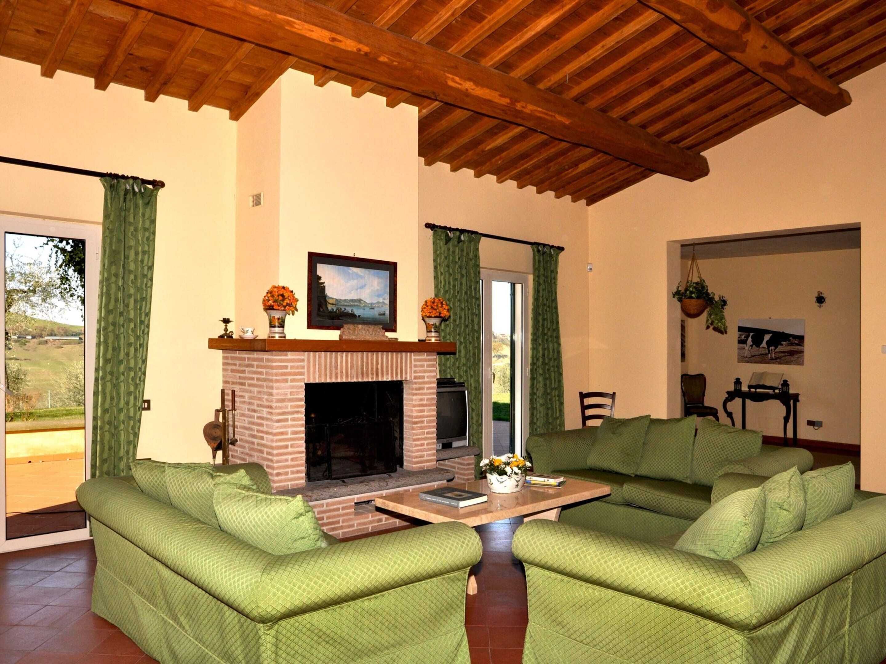A living room with a fireplace, green sofas, and a wooden ceiling.