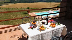Une table dressée à l’extérieur, avec vue sur un vignoble et une piscine.